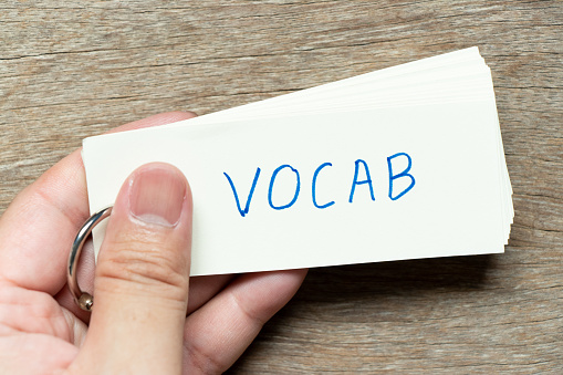 Man hold the flash card with handwriting word vocab on wood background