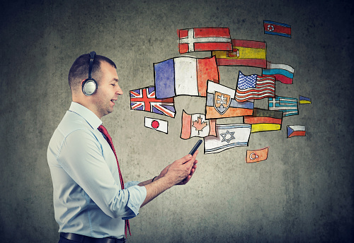Business man in headphones using mobile phone app learning different languages
