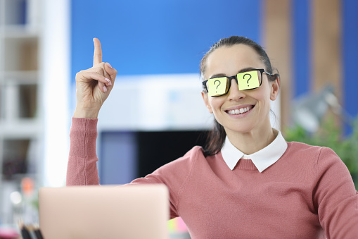 Woman has colored sticker with question mark on her glasses and holds her thumbs up. Search for new ideas and solutions in business concept