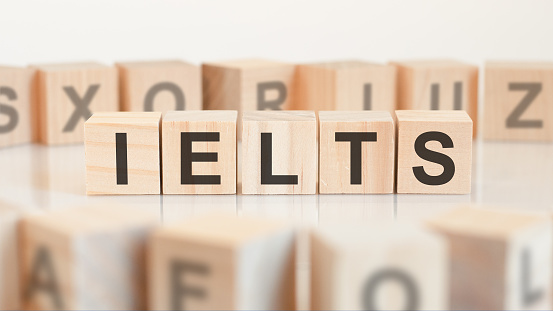 Toy wood blocks with letters IELTS on a table with light background, selective focus. IELTS - short for International English Language Testing System.